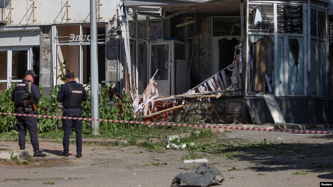 Police officers stand next to a building hit by what local authorities called a Ukrainian military strike, in Belgorod, Russia, May 9, 2024.