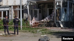 Police officers stand next to a building hit by what local authorities called a Ukrainian military strike, in Belgorod, Russia, May 9, 2024.