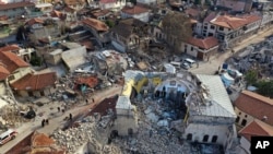 Warga Turki melewati masjid bersejarah Habib Najjar yang hancur saat gempa dahsyat, di kota tua Antakya, Turki, Sabtu, 11 Februari 2023. (Foto: AP)