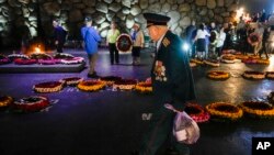 Un veterano de la Segunda Guerra Mundial pasa frente a las coronas colocadas en los marcadores de los campos de concentración, durante una ceremonia durante el Día del Recuerdo de los Mártires y Héroes del Holocausto en Jerusalén, Israel, el martes 18 de abril. 2023. 
