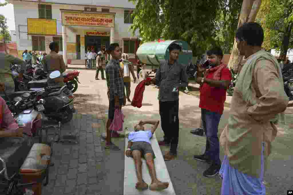 An elderly person suffering from heat related ailment lies on a stretcher waiting to get admitted outside the overcrowded government district hospital in Ballia, Uttar Pradesh state, India.