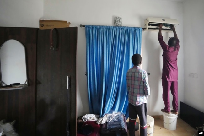 A technician works on an indoor air conditioning unit in Lagos, Nigeria, Thursday, July 18, 2024. (AP Photo/Sunday Alamba)