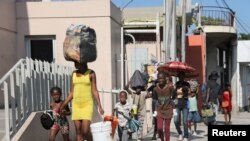 FILE - People walk to a shelter with their belongings, fleeing violence near their homes, in Port-au-Prince, Haiti, March 9, 2024. Due to gang violence, 53,125 people left the city between March 8 and March 27, according to the U.N.’s International Organizations for Migration.