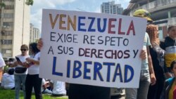 Una mujer muestra un cartel donde exige mejoras salariales al gobierno de Venezuela, durante una movilización por el Día del Trabajador en Caracas, el 1 de mayo de 2024.