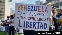 Una mujer muestra un cartel donde exige mejoras salariales al gobierno de Venezuela, durante una movilización por el Día del Trabajador en Caracas, el 1 de mayo de 2024.