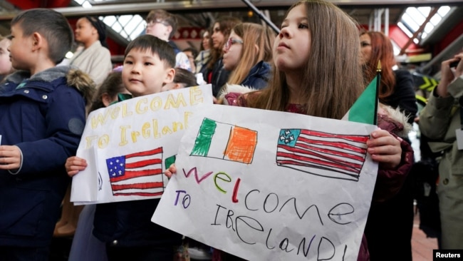 Las familias del personal de la embajada de los Estados Unidos sostienen pancartas cuando el presidente Joe Biden llega al Aeropuerto Internacional de Dublín, en Dublín, Irlanda, el 12 de abril de 2023. REUTERS/Kevin Lamarque