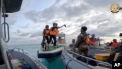 Penjaga Pantai China memegang kapak saat mendekati pasukan Filipina dalam misi pasokan di Beting Second Thomas, di Laut Cina Selatan yang disengketakan, 17 Juni 2024.(Angkatan Bersenjata Filipina via AP)