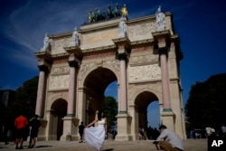 Tourists take pictures near the Arc de Triomphe du Carrousel at the 2024 Summer Olympics, July 28, 2024, in Paris, France.