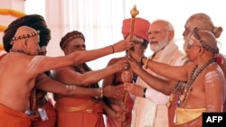 This handout photograph taken May 28, 2023 and released by the Indian Press Information Bureau (PIB) shows India's Prime Minister Modi with priests during the inauguration of the new parliament building in New Delhi. 