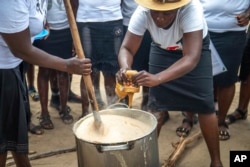 Women prepare porridge to feed to children at a feeding center in Mudzi, Zimbabwe, on July 2, 2024. In Zimbabwe, an El Nino-induced drought is affecting millions of people, and children are most at risk. (AP Photo/Aaron Ufumeli)