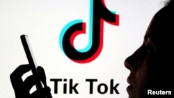 FILE - A person holds a smartphone as Tik Tok logo is displayed behind in this picture illustration taken Nov. 7, 2019. 