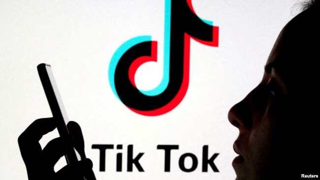 FILE - A person holds a smartphone as Tik Tok logo is displayed behind in this picture illustration taken Nov. 7, 2019.