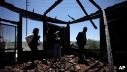 An international delegation examines a torched building as they tour the West Bank town of Turmus Ayya, days after a rampage by Jewish settlers, June 23, 2023. 