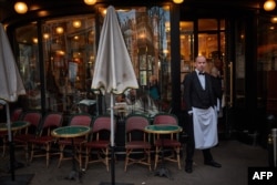 FILE - Seorang pelayan berdiri di teras Cafe de Flore, di pusat kota Paris, 28 Maret 2024. (Kiran Ridley / AFP)