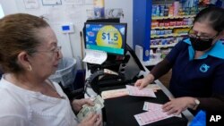 Mirta Herrera, right, sells lottery tickets, Aug. 7, 2023, at the Presidente Supermarket in the Little Havana neighborhood of Miami the day before the lottery's drawing. A player in Florida won a record $1.58 billion Mega Millions jackpot on Tuesday, the lottery announced.