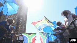 Supporters of the South African opposition party Democratic Alliance (DA) hold party flags as they march for their manifesto launch at the Union Buildings in Pretoria, on Feb. 17, 2024.