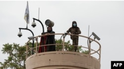 FILE - Taliban fighters keep watch from a tower at the US embassy as people (unseen) demonstrate against videos of allegedly showing Afghan refugees being beaten by Iranians went viral, near the Ahmad Shah Massoud square in Kabul, Apr. 12, 2022.