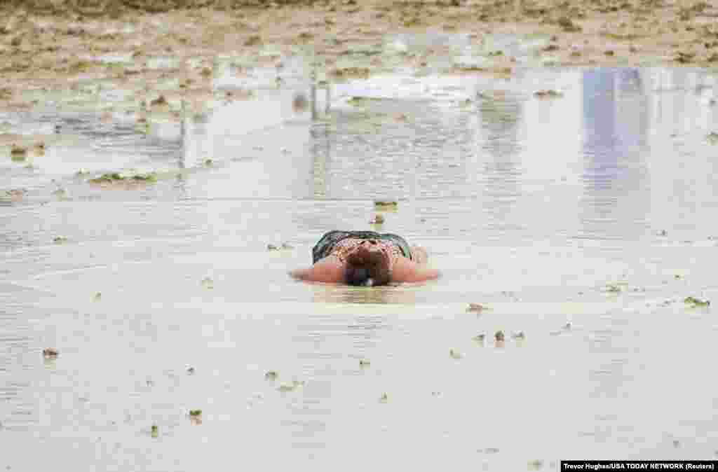 A Burning Man attendee lies down in the mud and water at the event in Black Rock City, in the Nevada desert, after a rainstorm, Sept. 2, 2023.