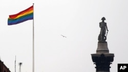 ARCHIVO - La bandera del arco iris, un símbolo de la comunidad LGBTQ+, ondea sobre un edificio al lado del monumento a la Columna de Nelson, a la derecha, en Trafalgar Square, en el centro de Londres, el 28 de marzo de 2014.