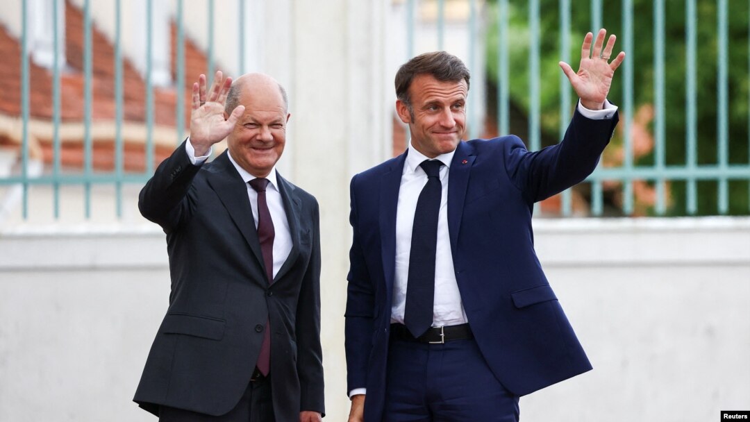 Kanselir Jerman Olaf Scholz dan Presiden Prancis Emmanuel Macron mekambaikan tangan saat bertemu di Istana Meseberg, di utara Berlin, Jerman, pada 28 Mei 2024. (Foto: Reuters/Liesa Johanssen)