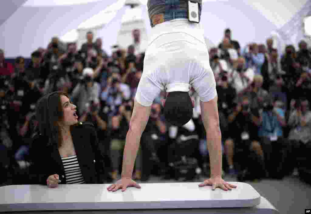 Billie Blain, left, reacts as Tom Mercier performs a handstand at the photo call for the film &#39;Le Regne Animal&#39; at the 76th international film festival, Cannes, southern France.