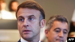 France's President Emmanuel Macron (L) gives a speech next to France's outgoing Minister for Interior and Overseas Gerald Darmanin (R) as they meet French police officers during the Paris 2024 Olympic Games in Paris, July 27, 2024.