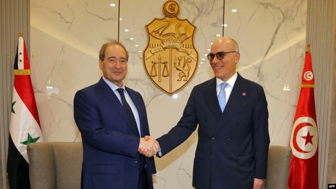 A handout photo provided by the Tunisian Foreign Ministry shows Tunisian Foreign Minister Nabil Ammar, right, greeting his Syrian counterpart Faisal Mikdad at Tunis–Carthage International Airport, April 17, 2023.