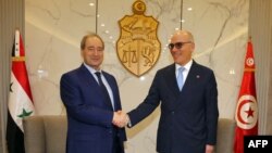 A handout photo provided by the Tunisian Foreign Ministry shows Tunisian Foreign Minister Nabil Ammar, right, greeting his Syrian counterpart Faisal Mikdad at Tunis–Carthage International Airport, April 17, 2023.
