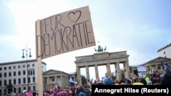 Seorang individu memegang plakat yang bertuliskan 'For democracy' saat demonstrasi ekstremisme kanan dari Partai Alternatif untuk Jerman (AfD) di Berlin, Jerman, 14 Januari 2024. (Foto: REUTERS/Annegret Hilse)