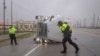 Сотрудники полиции борются с сильными ветрами, вызванными ураганом «Берил», когда они ищут пассажиров перевернутого грузовика с полуприцепом во Фрипорте, штат Техас, США, 8 июля 2024 года.