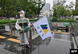 Seorang pejabat pemerintah Korea Selatan memegang bendera pertahanan sipil, memandu warga ke fasilitas bawah tanah setelah sirene serangan udara dibunyikan selama latihan pertahanan sipil melawan kemungkinan serangan artileri Korea Utara di Seoul, 23 Agustus 2023. (Jung Yeon-je / AFP )