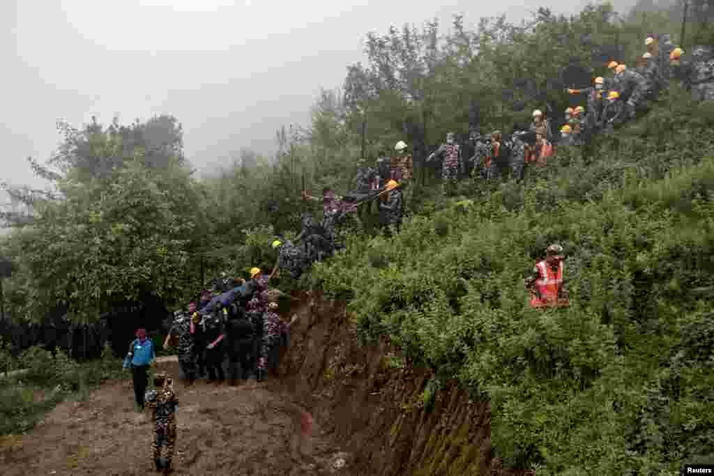 Para anggota pasukan keamanan mengevakuasi jenazah para korban di lokasi kecelakaan helikopter di pinggiran ibu kota Kathmandu, Nepal. (Reuters)&nbsp;