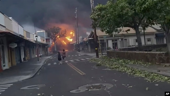 People watch as smoke and flames fill the air from raging wildfires on Front Street in downtown Lahaina, Maui on Tuesday, Aug. 8, 2023. (Alan Dickar via AP) Keep aspect ratio