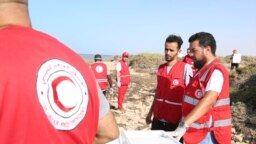 FILE - Aid workers assist migrants near the Libyan-Tunisia border, July 23, 2023. 
