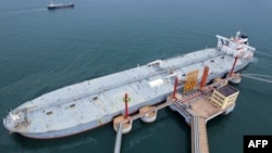 FILE - An oil tanker unloads imported crude oil at Qingdao port in China's eastern Shandong province on May 9, 2022. 