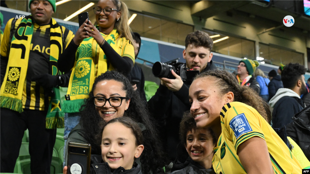 Solai Washington, mediocampista de Jamaica, posa para una selfie con aficionados, después de que su equipo clasificara para los octavos de final tras el partido entre Jamaica y Brasil.