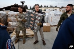 Secretary of State Antony Blinken helps U.S. military personnel carry aid, at Incirlik Air Base near Adana, Turkey, Feb. 19, 2023.