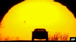 FILE - A motorist is silhouetted against the setting sun on the eve of the vernal equinox, in Shawnee, Kansas, March 19, 2023. Spring gets its official start March 19, 2024, in the Northern Hemisphere. 