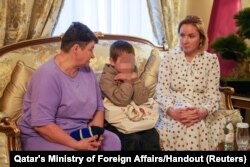 A 7-year-old Ukrainian boy sits by his grandmother, left, and Russia's Commissioner for Children's Rights, Maria Lvova-Belova, after being released to Qatari diplomats, at Qatar's embassy in Moscow, Russia, Oct. 13, 2023. (Qatar's Ministry of Foreign Affairs/Handout via Reuters)