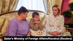 FILE — In this photo taken in Moscow, Russia, a Ukrainian boy repatriated from Russia to Ukraine sits next to his grandmother, left, and Russian Commissioner for Children's Rights Maria Lvova-Belova, Oct. 13, 2023. (Qatar's Ministry of Foreign Affairs/Handout via Reuters)