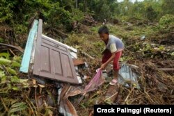Seorang anak laki-laki menyelamatkan barang-barangnya dari reruntuhan rumahnya yang terkena gempa dan tsunami di sebuah desa di Munte, Kabupaten Mentawai, Sumatera Barat 29 Oktober 2010. (Foto: Reuters/Crack Palinggi)