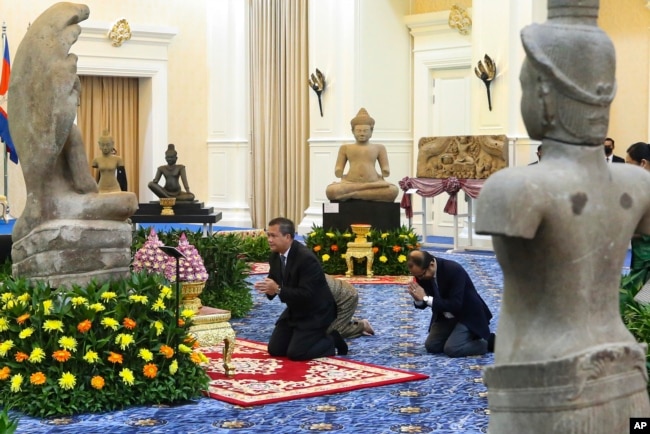 In this photo released by Agence Kampuchea Press (AKP), Cambodian Prime Minister Hun Manet prays before a Buddha statue during a ceremony for the return of artifacts at Peace Palace in Phnom Penh, Cambodia, Thursday, Aug. 22, 2024. (AKP via AP)