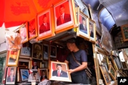 Seorang pedagang menunjukkan salah satu potret Presiden terpilih Indonesia dan Menteri Pertahanan Indonesia Prabowo Subianto yang dijual di sebuah pasar di Jakarta, Rabu, 24 April 2024. (AP/Achmad Ibrahim)