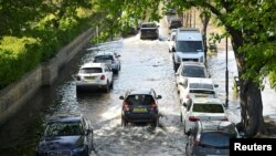 FILE - Water floods a road along the River Thames in London, Britain, April 19, 2023. Britain is accelerating plans to protect London from flooding caused by a warming climate and rising sea levels, advancing its plan to protect the city center by 15 years.