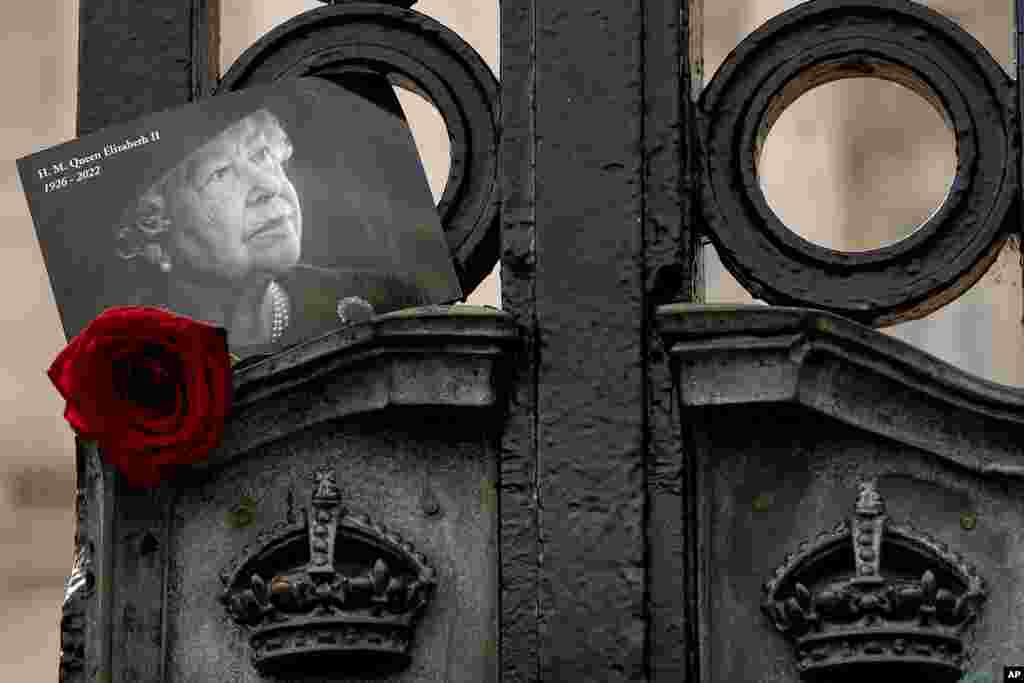 A tribute to Britain&#39;s Queen Elizabeth II is tucked into the gates of Buckingham Palace in London as Britain marks the first anniversary of her death. (AP Photo/Kirsty Wigglesworth)