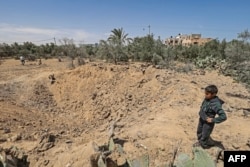 A boy stands near a crater in Rafah in the southern Gaza Strip, on May 14, 2023, amid a cease-fire ending five days of deadly fighting between Israel and the Palestinian Islamic Jihad militant group.