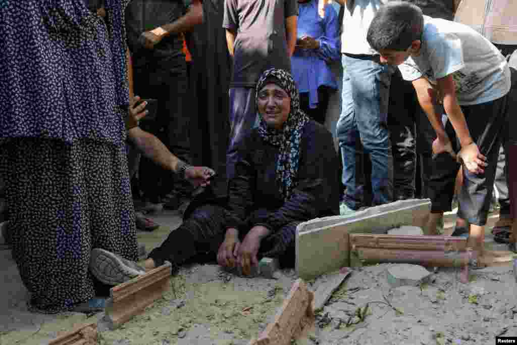 A relative of a Palestinian killed during the Israeli military offensive and buried earlier at al-Amal Hospital, reacts next to a grave as preparations are made to exhume the body for reburial in a cemetery, in Khan Younis in the southern Gaza Strip.