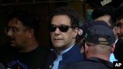 Pakistan&#39;s former Prime Minister Imran Khan, center, is escorted by security officials as he arrives to appear in a court, in Islamabad, Pakistan.&nbsp;A high court in Islamabad has granted Khan a two-week reprieve from arrest in a graft case and granted him bail on the charge.