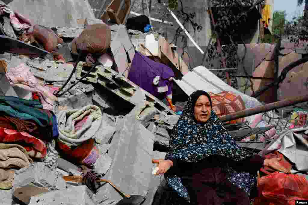 A woman makes a motion with her arms next to rubble, following deadly Israeli strikes in the northern Gaza Strip.