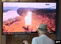 Seorang pria menonton layar televisi yang menayangkan siaran berita uji coba rudal Korea Utara, di stasiun kereta api di Seoul pada 26 Juni 2024. (Foto: AFP)